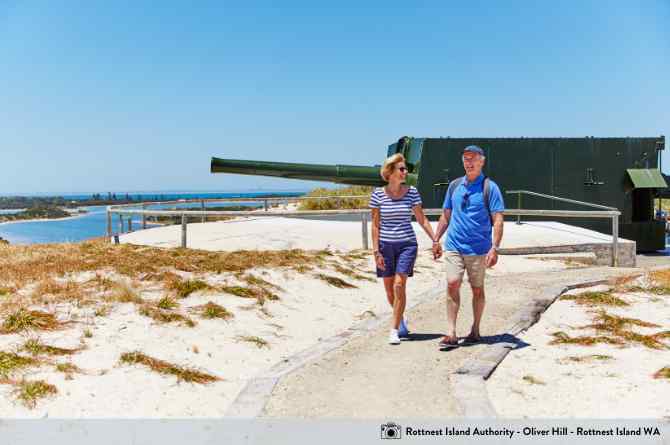 couple walking along path next to beach 
